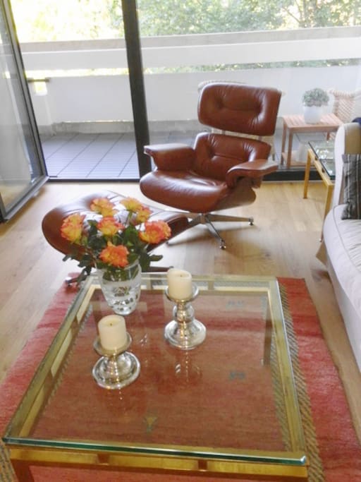 The living room comprises a comfy armchair as well as a couch that are next to the big glass door, which leads to the 1st balcony.