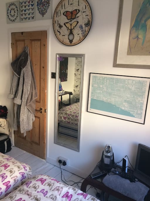 There is a dressing gown, tv and wall mirror in the room.