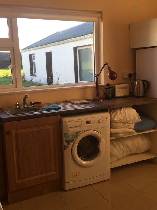 Food preparation, washing machine, bedding store. View to North across back garden and outbuilding.