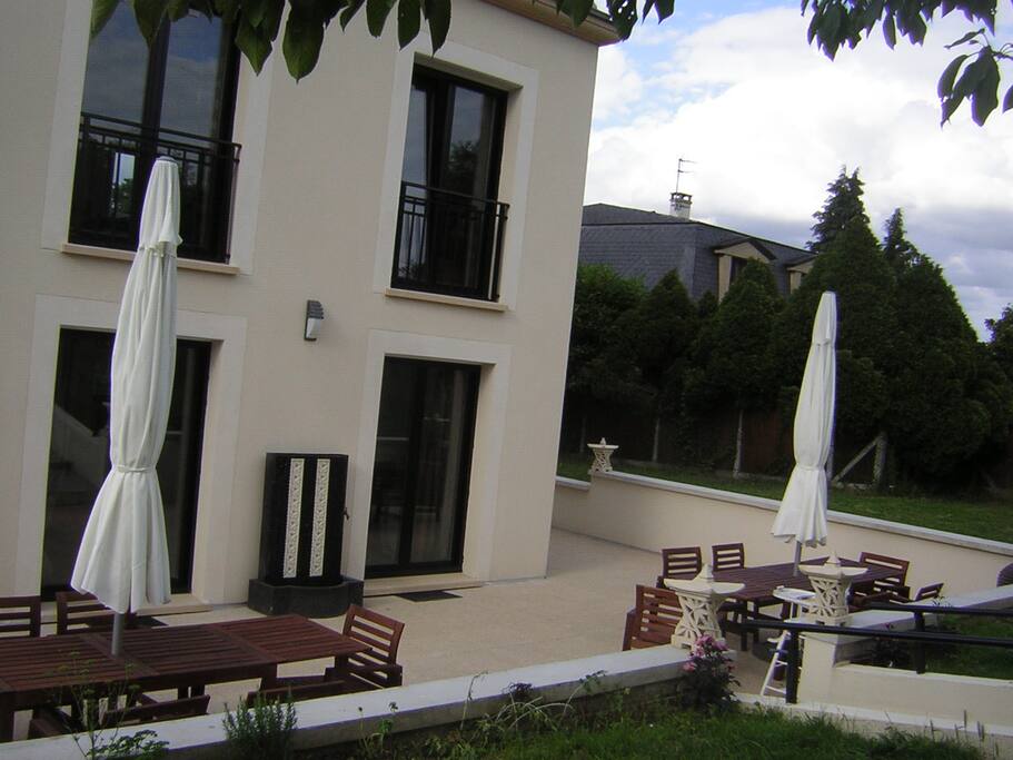 grande terrasse au tour de la demeure, équipée de mobilier de jardin, barbecue