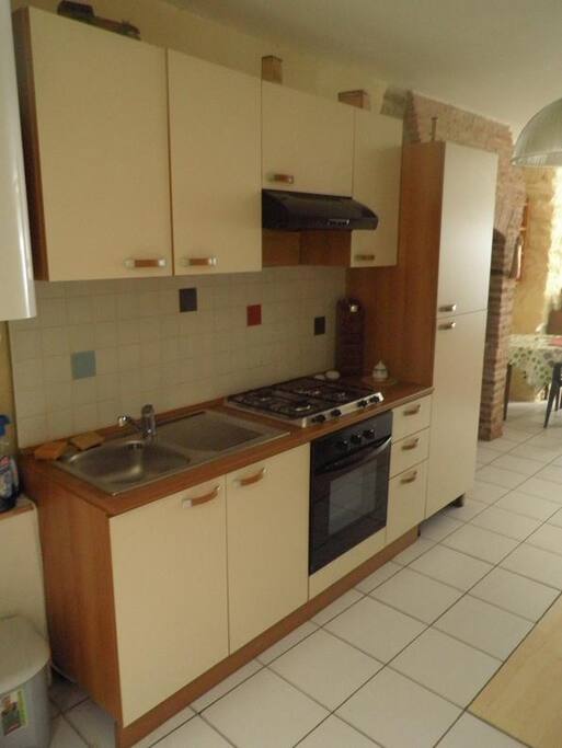 Cusine encastrée. Cuisinière gaz, hotte. Frigo dans placard de droite.