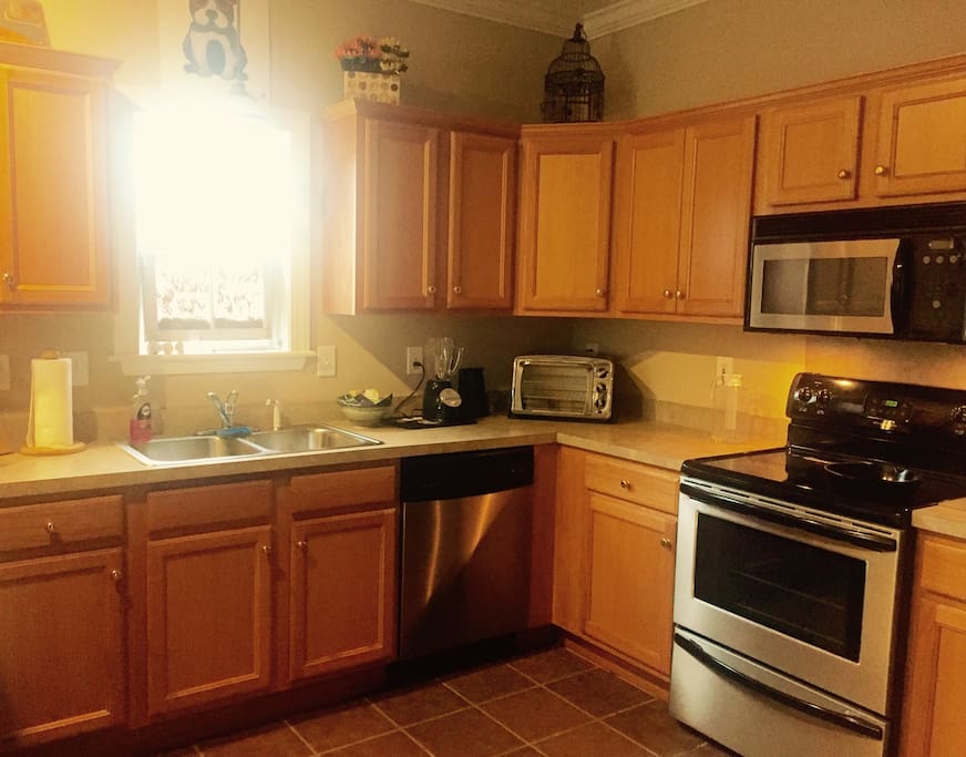 The kitchen has a fridge, dishwasher, stove, dual sink, coffee maker, etc. Floor is Spanish tile and to the right is a laundry room with washer and dryer.