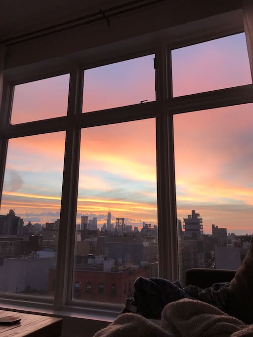 Manhattan skyline view at sunset from panoramic windows in living room.