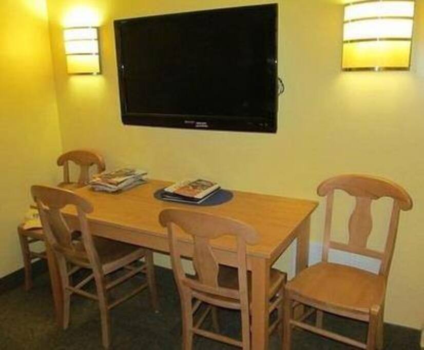 Living room has a table that seats 4 and a flat screen TV.