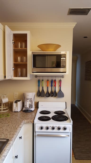 Kitchen with oven and microwave. Coffee maker, toaster, cookware, dishware, and utensils.