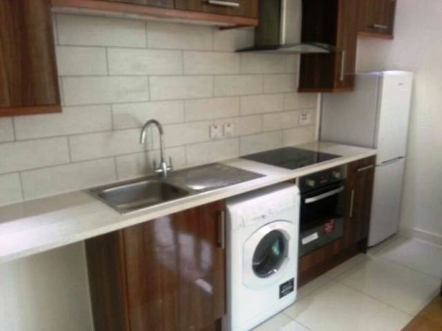 Kitchen unit provided with electric cooker, washing machine and fridge freezer.