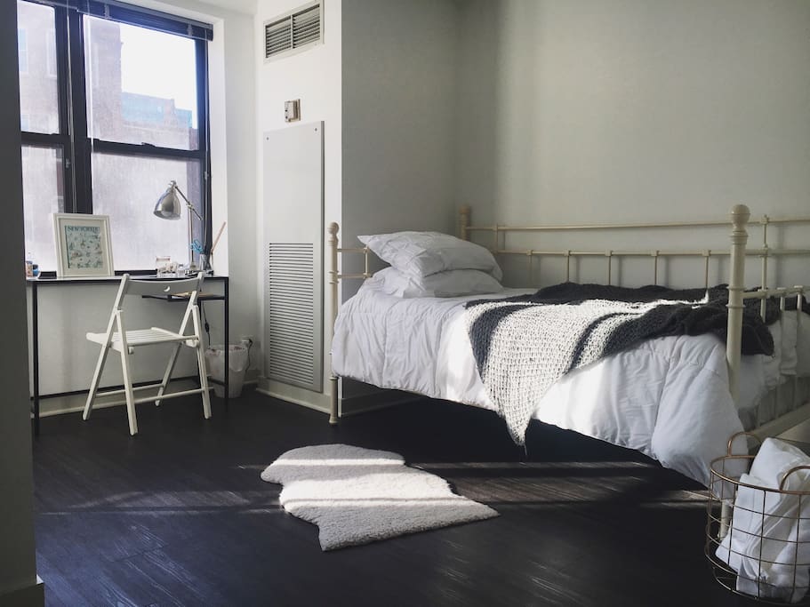 The cozy and bright bedroom features a twin bed and workspace