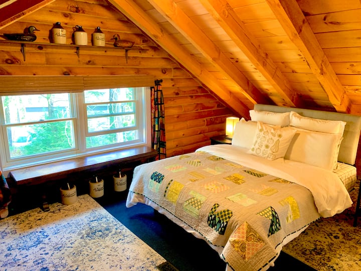 El dormitorio del tercer piso, con una cama tamaño queen y un ambiente de cabaña serio.