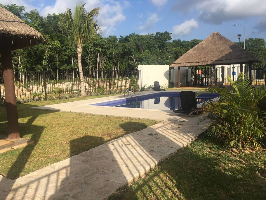 Alberca con palapa, asador y camastros.