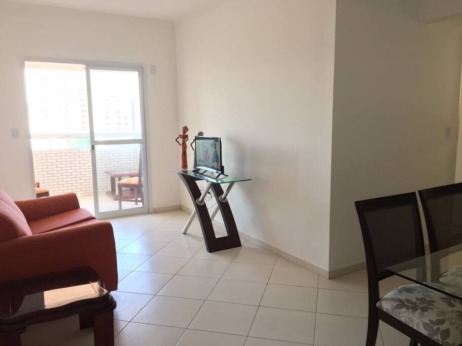 Sala com sofá, TV e mesa para seis pessoas