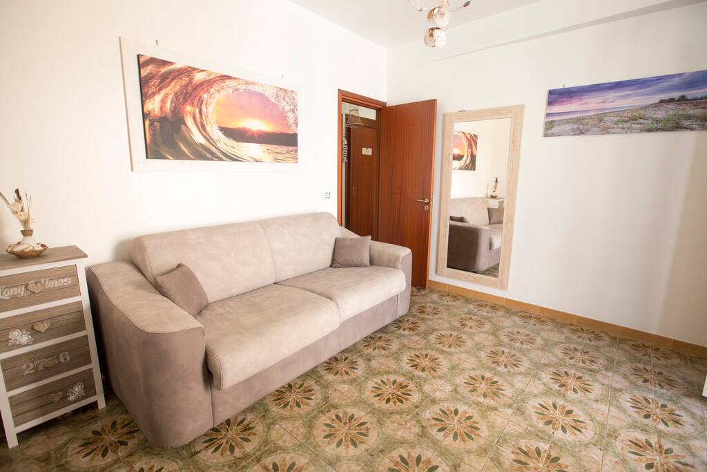 Soggiorno con divano-letto matrimoniale e balcone vista mare