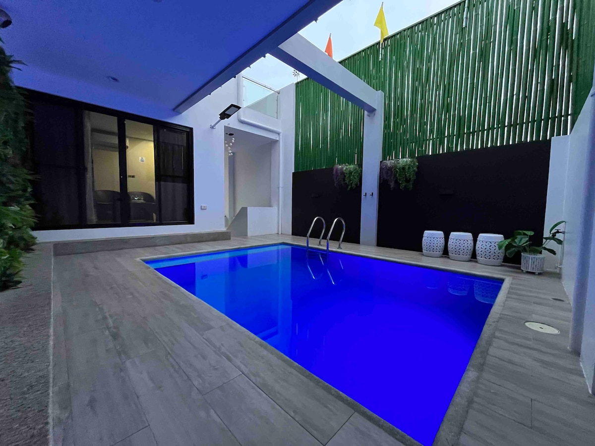 A private plunge pool is surrounded by sleek tile flooring and a modern design. Vibrant blue water reflects the ambient light, and decorative elements are present along the edges, providing a serene and inviting space for relaxation.