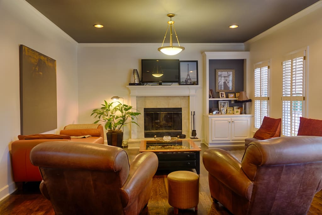 Family room with leather sofa and club chairs, wood burning fireplace and flat screen TV.