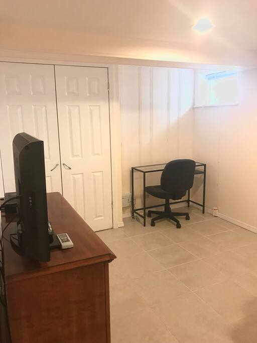 Samsung TV, closet, and 2 desks in renovated bedroom.