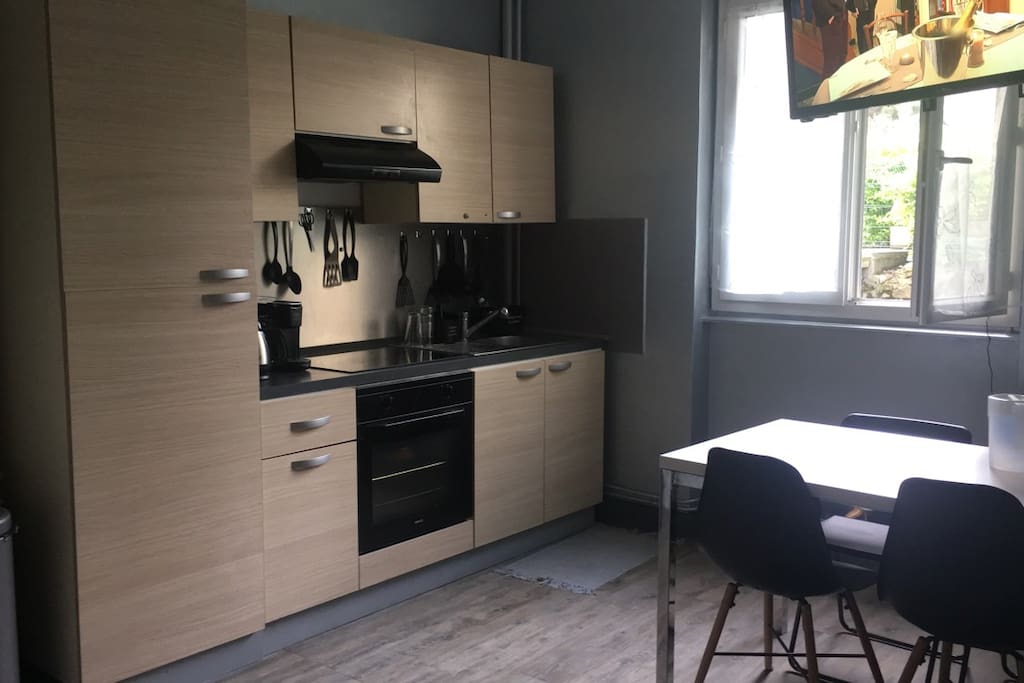 Cuisine ouverte sur le salon équipée d’un micro-onde, d’un congélateur-réfrigérateur, d’un grill-pain et d’un appareil à croque-monsieur. La fenêtre de la cuisine donne sur la cour.