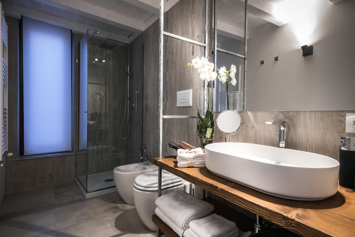 Bagno moderno con lavabo d'appoggio su mensola in legno e doccia in vetro