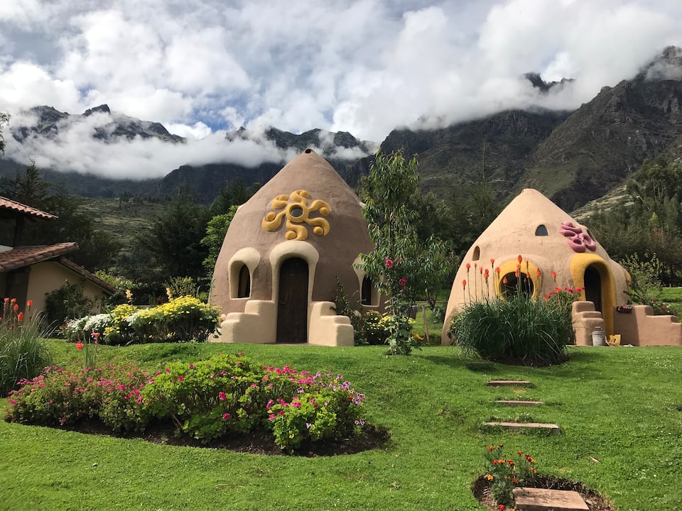 Dome House in Sacred Valley, dried earth huts with decorative yellow and pink moldings and lush green landscape.