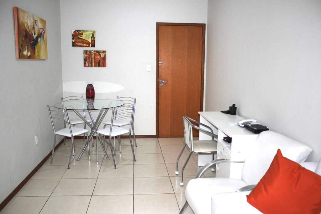Sala de estar espaçosa com televisão, mesa e escrivaninha para trabalho ou estudo.