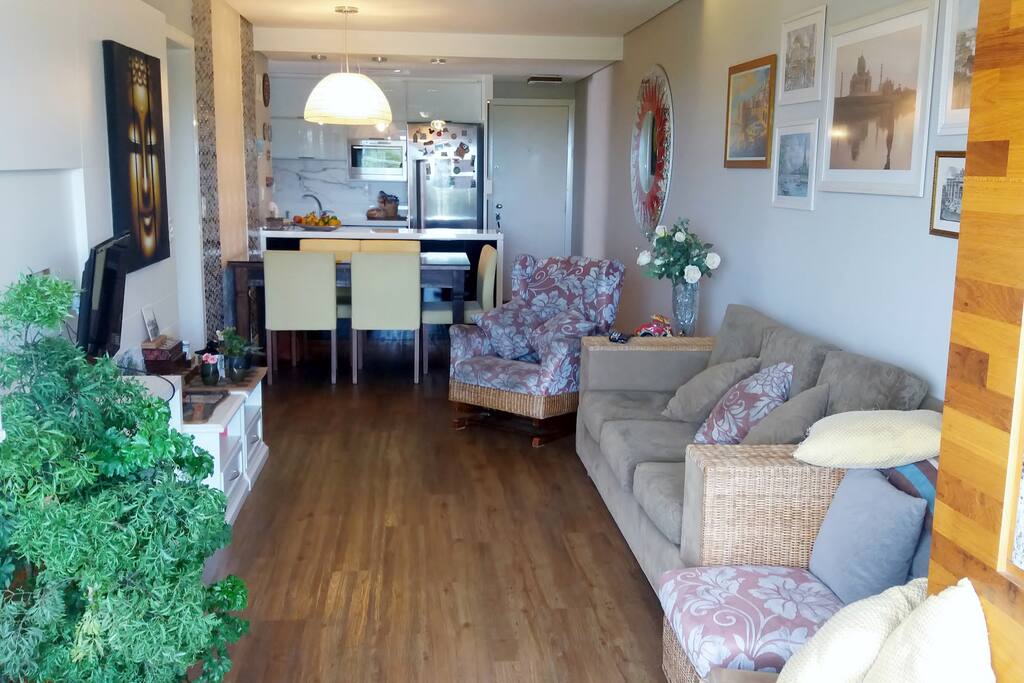 Sala do apartamento com tv a cabo, varanda com churrasqueira. Com a cozinha integrada.