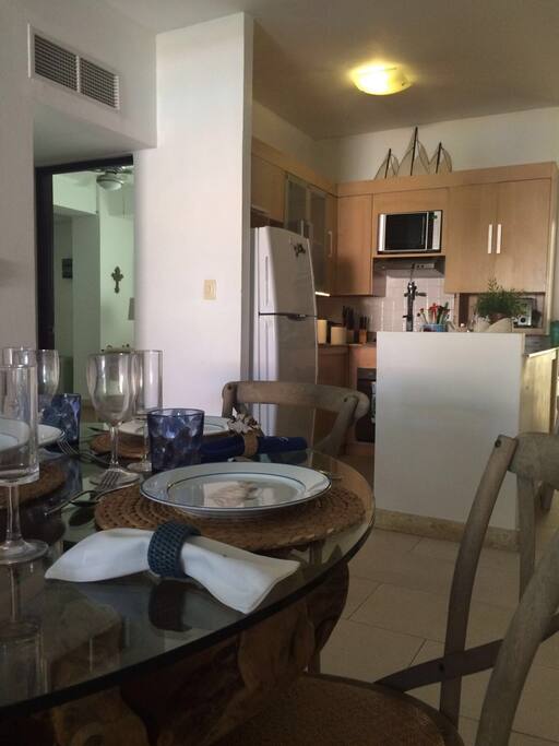 Partial view of crystal dinning table,kitchen,and the entrance door open for the second bedroom.