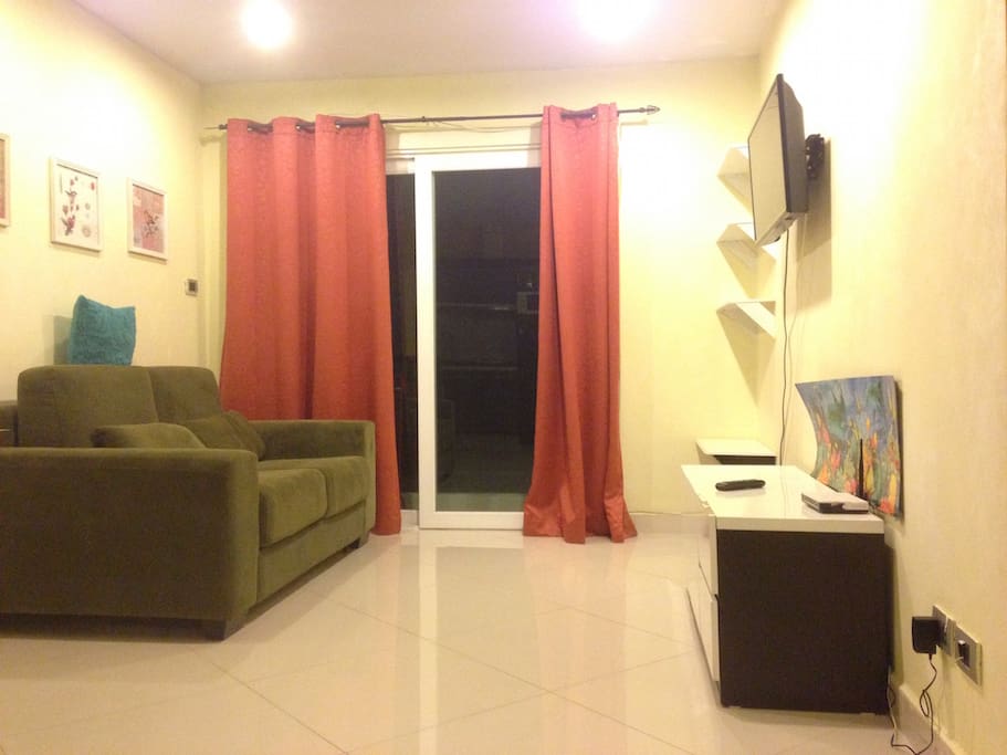 Cozy living room with sofa-bed, TV, dining table and chairs, balcony access