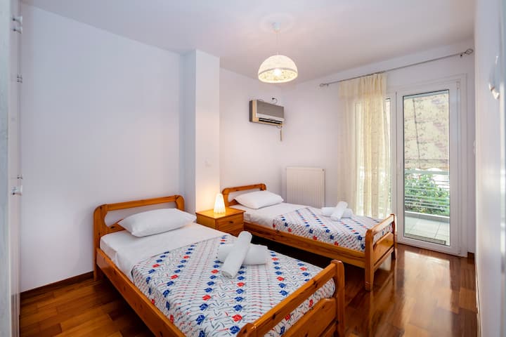 Ett ljust och inbjudande sovrum med två mysiga enkelsängar med färgglada sängkläder. Rummet kompletteras med naturligt ljus som strömmar genom stora fönster, vilket erbjuder en lugn utsikt och tillgång till en privat balkong för din avkoppling.