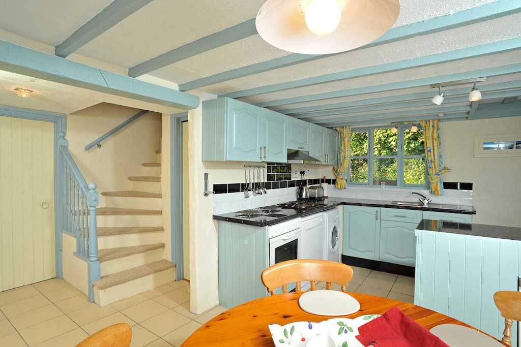 Kitchen and dining room, with dishwasher, washing machine, oven hob and microwave leading onto bathroom and sweeping staircase
