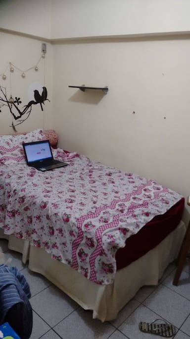 Mesa para estudos e estante de livros ao lado da cama.