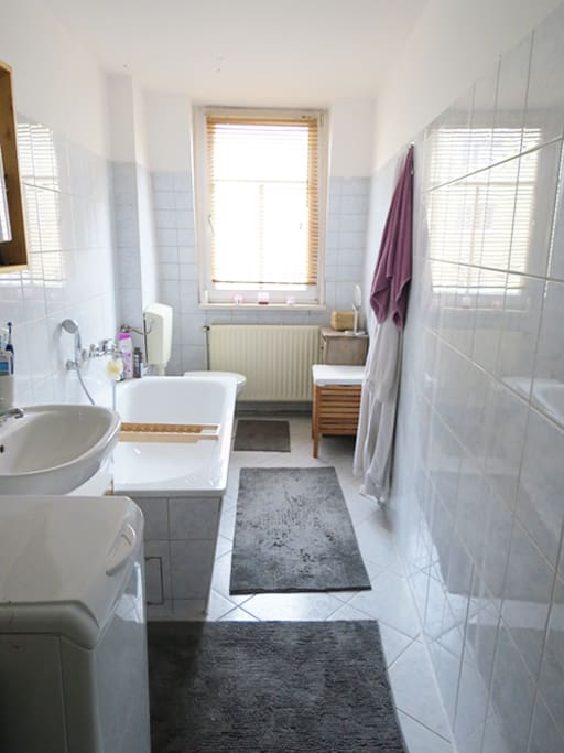 Bad mit Waschmaschine und Badewanne, Handtücher werden gestellt.