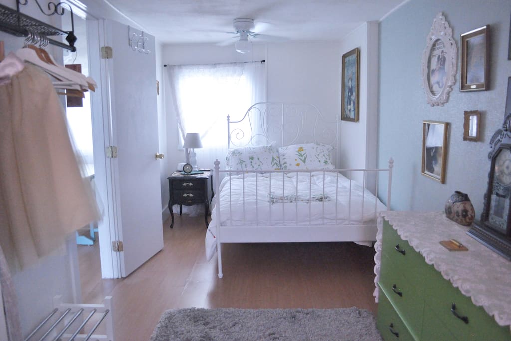 Bedroom with full bed, dresser, garment rack and bedside table