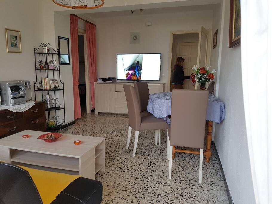 Wohnzimmer mit Esstisch, Fernseher, Schlafcouch und Zugang zum Südbalkon