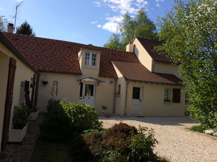 Photo de la maison vue de l entrée du portail, Avec partie extension sur la droite, chambre en partie masquée par le feuillage, en bas à droite.