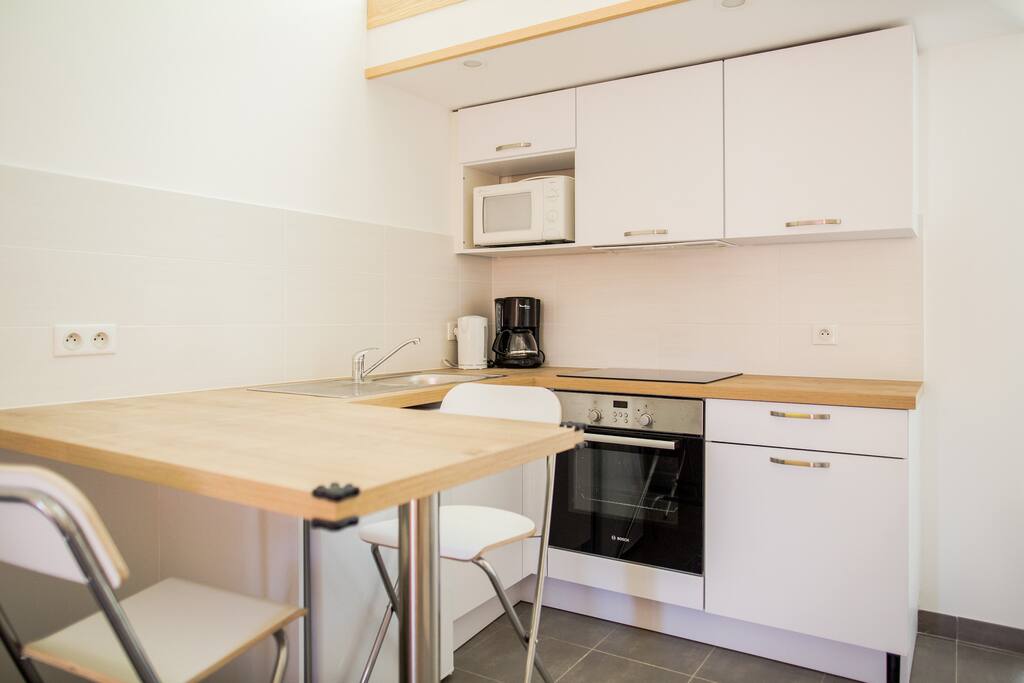 Vrai cuisine aménagée avec bar et 4 chaises de bar.