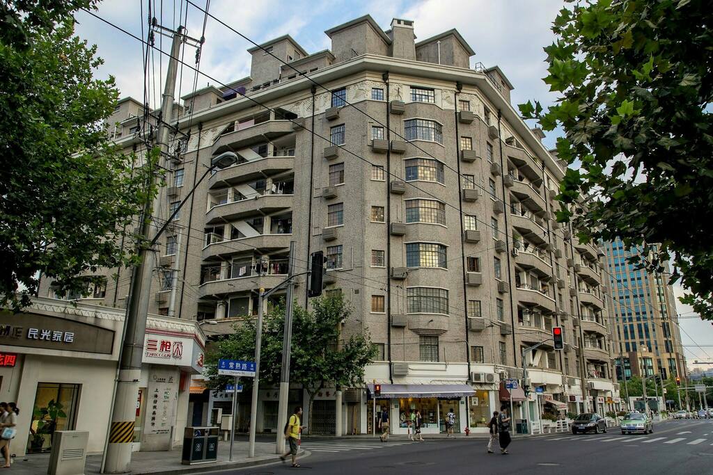 逸家所在的建筑叫瑞华公寓(Savoy Apartments),原为赛华公寓,1928年竣工,由法商营造公司(Minutti and Co.)设计,装饰艺术派风格,已被上海市人民政府被定为上海市首批历史保护建筑。房子在当年即有电梯,足以显示出它主人的身份,解放后成为上海市委其中的一个家属院,百年历史巨变,他尊贵而独特的气质具有极强的海派个性和魅力。此图是本建筑现状照片。