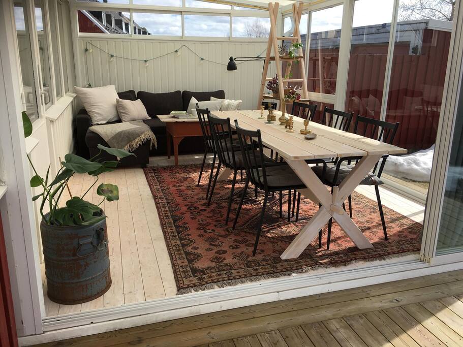 Inglasad veranda med bord och plats för sex personer, en soffa att avnjuta kvällskaffet i eller ligga och slappa i när barnen har somnat.