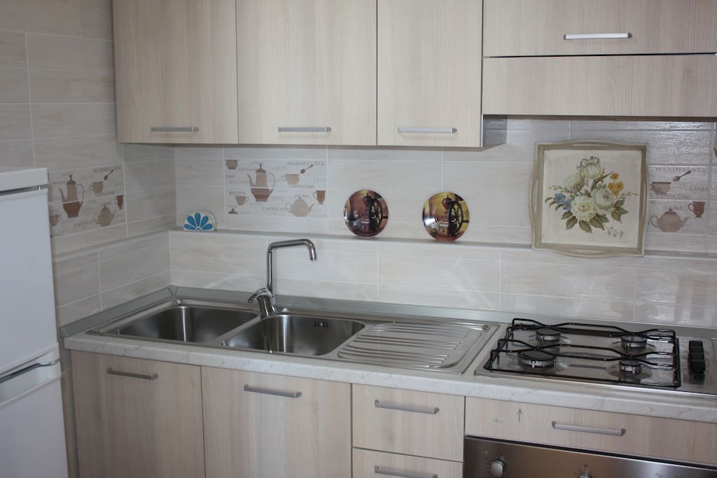 Cucina non abitabile dotata di frigorifero, forno, pentole, posate e bicchieri.