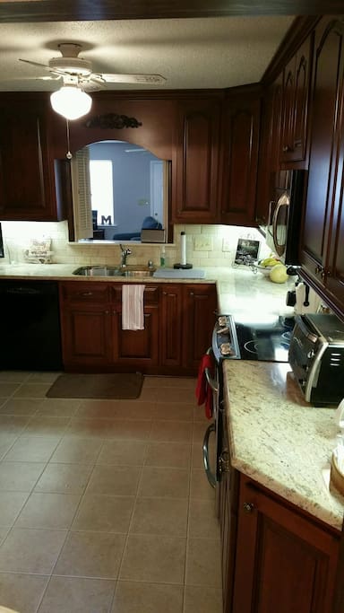 Beautiful Gourmet Kitchen with custom cabinets, granite countertops, tile floor & stainless appliances. Includes cookware, glassware, dishes, and utensils. (View 1)
