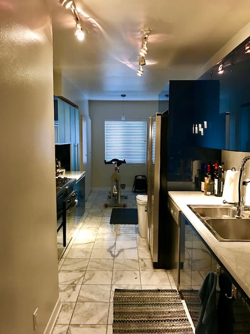 Fully equipped kitchen with microwave, stove, fridge. Home gym in the background.