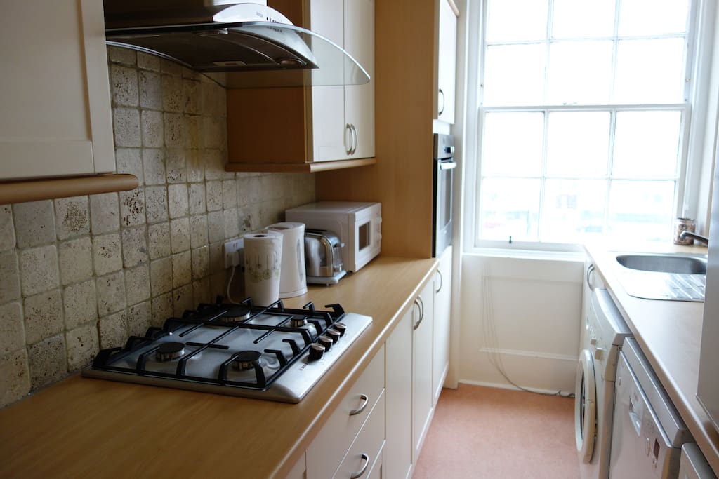 Kitchen with all appliances, including dishwasher, washing machine, microwave, oven, fridge, freezer.