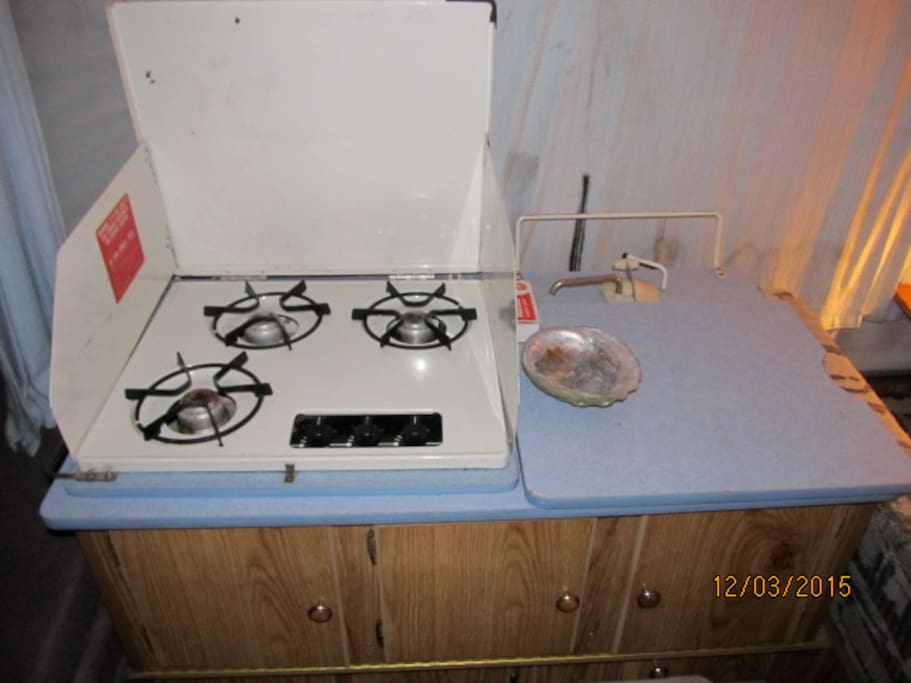 Gas stove and kitchen is equipped with pots, pans, plates, silverware, cups, bowls, etc.