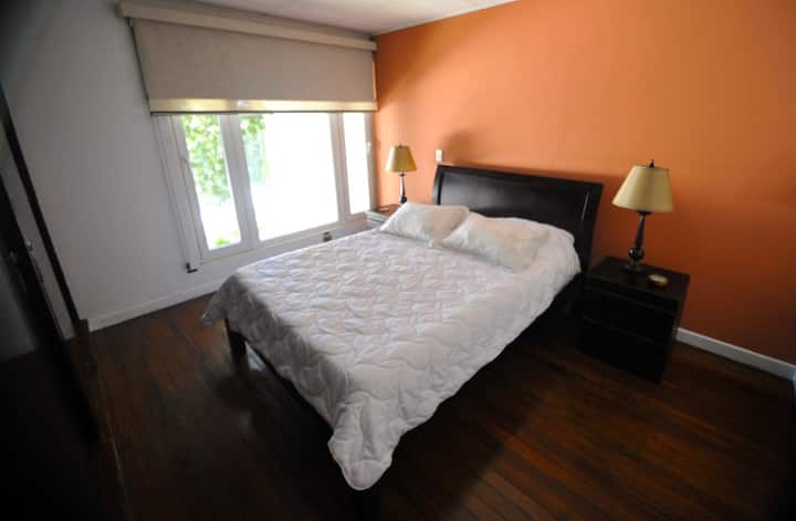 Ni pana na yenye starehe, iko kwenye ghorofa ya pili, ina kitanda cha ukubwa wa kifalme, meza za kando ya kitanda zilizo na taa, mapazia ya kuzima mwanga kwa ajili ya kupumzika kabisa, madirisha ya kuzuia sauti kwa ajili ya utulivu zaidi na feni ya kuhakikisha hewa inakuwa baridi.