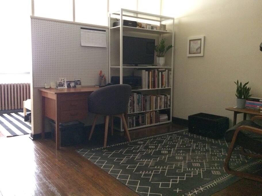 Living area with desk, reading chair, and television