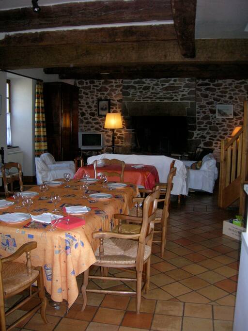 grande salle commune avec cheminée d'un coté et cuisine de l'autre.