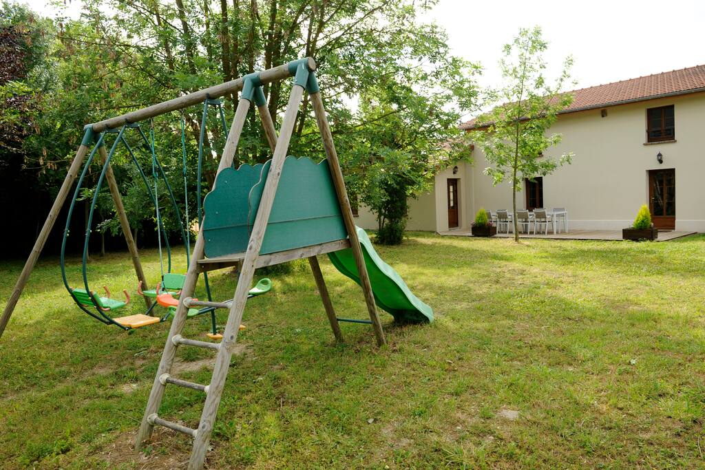 Jardin clôturé avec terrasse et portique balançoire-toboggan pour la plus grande joie des enfants