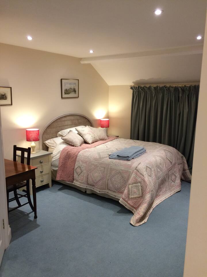 غرفة نوم رئيسية بسرير مزدوج وأدراج وخزانة ملابس ومكتب وكرسي وغرفة استحمام داخلية.