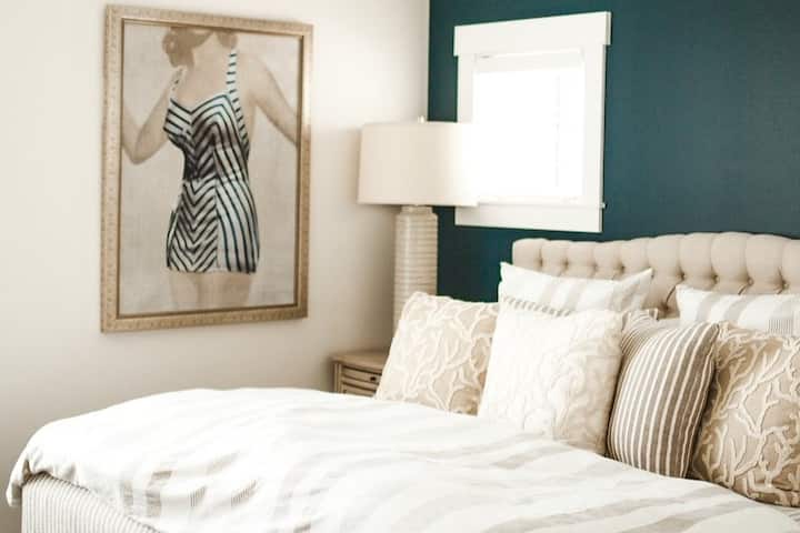 Primary bedroom with king mattress, en suite bathroom with tub/shower combo, and soaring 12ft ceilings. Night stands include charging stations in the top drawers with charging cords provided.