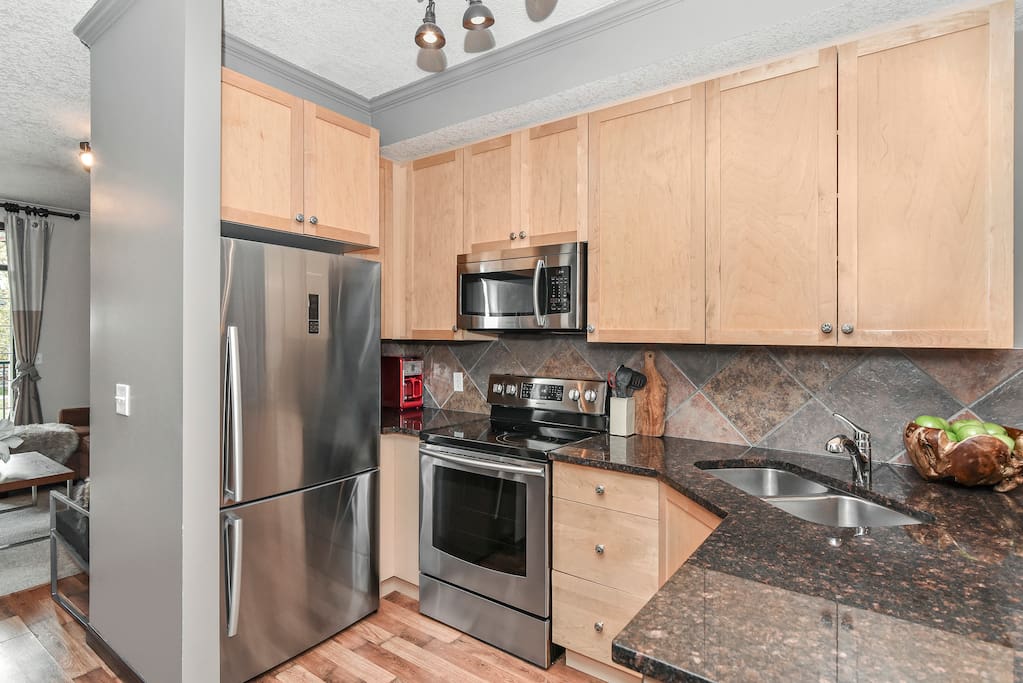 Fully stocked kitchen with new stainless steel appliances.