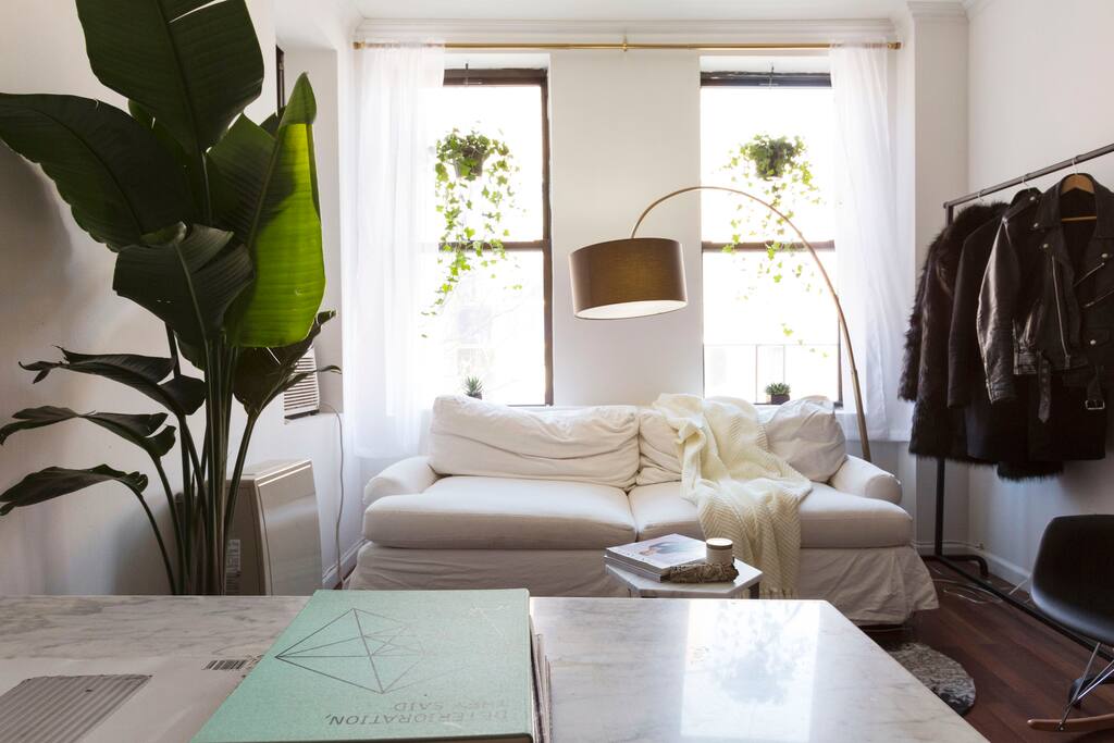 Foliage and designer furniture bring the spacious living room to life. Beautiful white marble table for dining in and a clothing rack (with hangers) for your use. Couch pulls out to a queen bed.