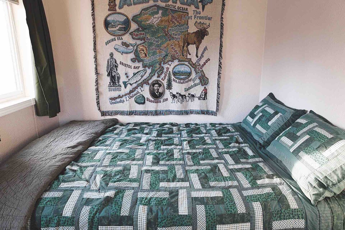 Kitanda cha ukubwa wa malkia katika chumba kidogo cha kulala. Chumba hiki kina mwangaza mkubwa kutoka kwenye madirisha. 