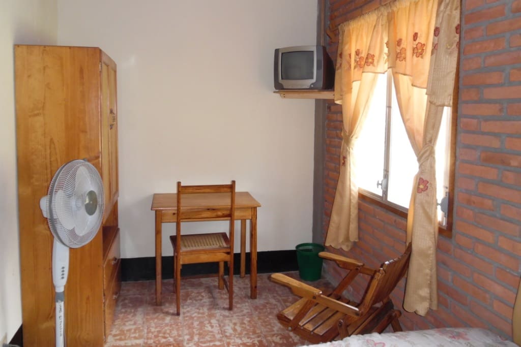 Inside family room with small desk, cable color TV, wardrobe and floor fan